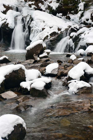 A small active waterfall. Clean mountain stream, snowy winter landscape, wildlife backgroundの写真素材