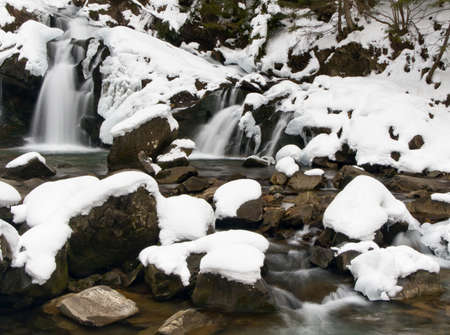 A small active waterfall. Clean mountain stream, snowy winter landscape, wildlife backgroundの写真素材