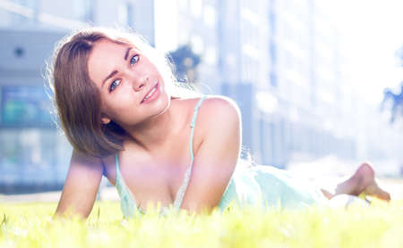 Pretty brunette girl wearing elegant dress relaxing outdoor in green grass and smells aromatic lemon or lime citrusの写真素材