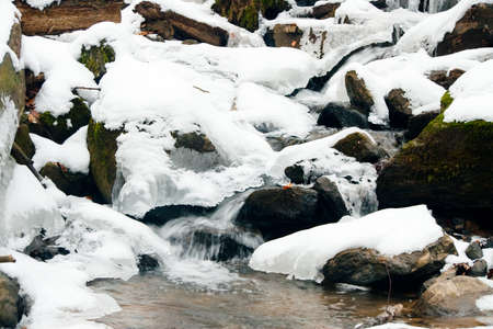 A small active waterfall. Clean mountain stream, snowy winter landscape, wildlife backgroundの写真素材