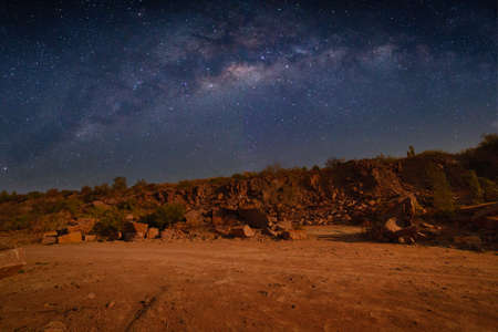 Milky Way over a lake in a granite quarry at night. Summer landscape with huge boulders, trees, purple sky with milky way and stars, beautiful reflection in the water. Ukraine. Space and nature.の写真素材