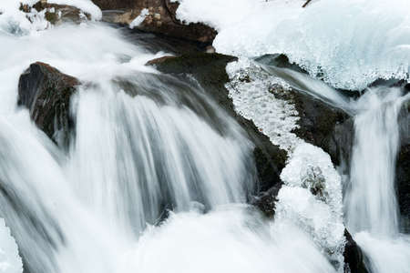 A small active waterfall. Clean mountain stream, snowy winter landscape, wildlife backgroundの写真素材