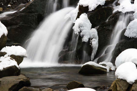A small active waterfall. Clean mountain stream, snowy winter landscape, wildlife backgroundの写真素材