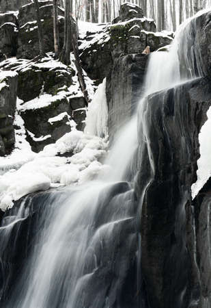 A small active waterfall. Clean mountain stream, snowy winter landscape, wildlife backgroundの写真素材