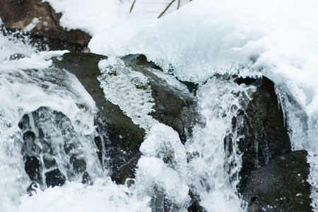 A small active waterfall. Clean mountain stream, snowy winter landscape, wildlife backgroundの写真素材