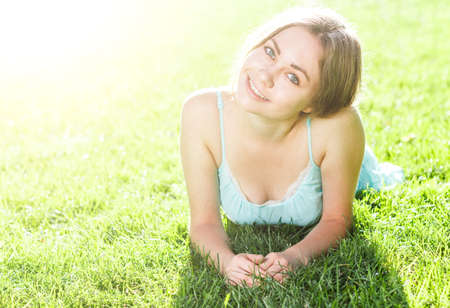 Pretty brunette girl wearing elegant dress relaxing outdoor in green grass and smells aromatic lemon or lime citrusの写真素材