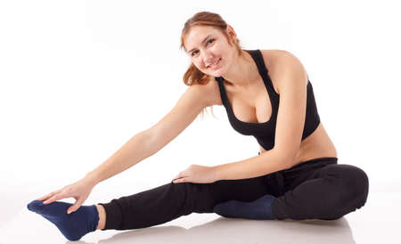 Female fitness model excercising in studio with dunbell weights and doing a floor routine of stretches and lifts on a matt.の写真素材