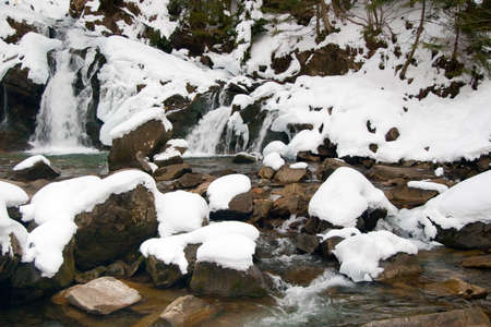 A small active waterfall. Clean mountain stream, snowy winter landscape, wildlife backgroundの写真素材