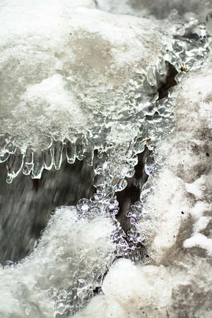 A small active waterfall. Clean mountain stream, snowy winter landscape, wildlife backgroundの写真素材