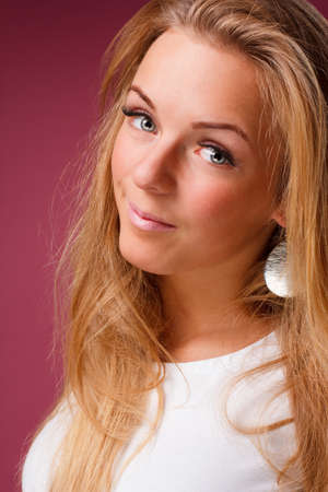 Fashion portrait of elegant young woman with curly blonde hair over pink backgroundの写真素材