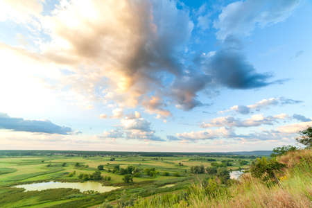 A beautiful valley with a river, blue sky with large clouds and bright sun. Aerial UHD