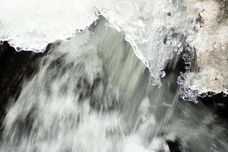 A small active waterfall. Clean mountain stream, snowy winter landscape, wildlife background