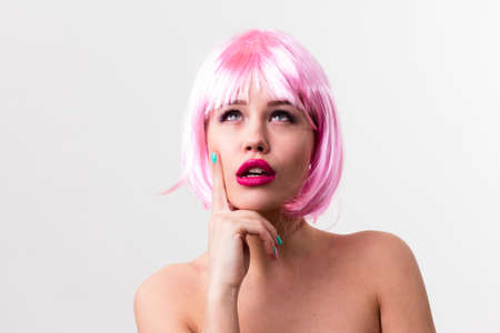 Face of a young woman with bright makeup on a pink background with gathered hair in a smooth ponytail.の写真素材