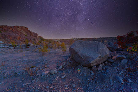 Milky Way over a lake in a granite quarry at night. Summer landscape with huge boulders, trees, purple sky with milky way and stars, beautiful reflection in the water. Ukraine. Space and nature.の写真素材