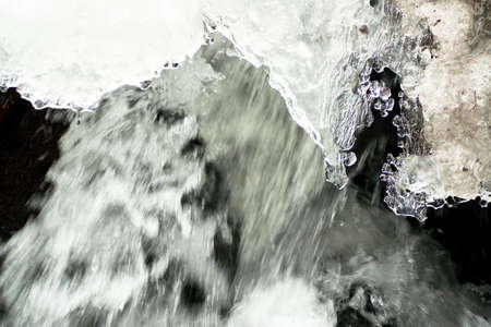 A small active waterfall. Clean mountain stream, snowy winter landscape, wildlife background