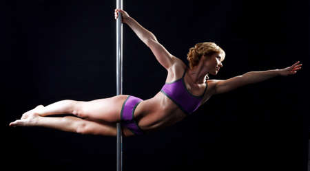The strong and graceful young girl performing acrobatic exercises on pylonの写真素材