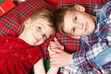 Portrait of happy boy in his sister embrace, both looking at camera on Christmas eveningの写真素材