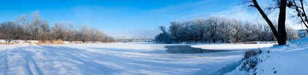 Photo the snow-covered river did not freeze in winter.The river flows in winter. Snow on the branches of trees. Reflection of snow in the river. Huge snowdrifts lie on the Bank of the stream.の写真素材