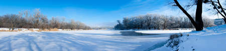 Photo the snow-covered river did not freeze in winter.The river flows in winter. Snow on the branches of trees. Reflection of snow in the river. Huge snowdrifts lie on the Bank of the stream.の写真素材