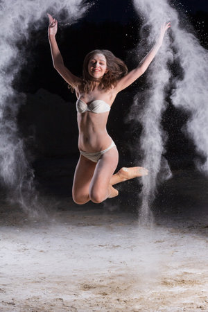 Woman ballet dancer on black background theater with powder dustの写真素材