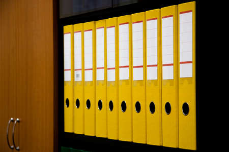 row of folders for papers and documentation on a shelf in the officeの写真素材