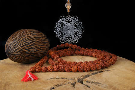 Indian art - tin mandala, prayer beards from Rudraksha, Foxtail palm seed on teak wood and black backgroundの写真素材