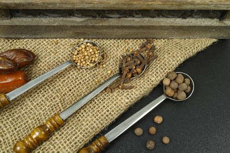 Set of spices and seasonings, 3 vintage metal spoons on sacking and black backgroundの写真素材