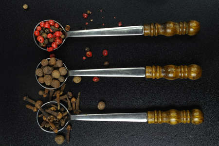 Set of spices and seasonings, 3 vintage metal spoons on black backgroundの写真素材