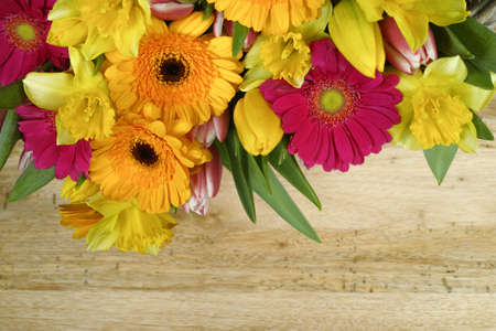 Multicolored bouquet tulips, narcissus, gerbera flowers on wooden tableの写真素材