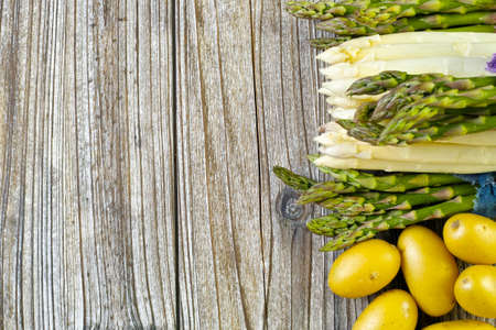 Bunch of fresh white and green asparagus and potatoes on wooden background, rustic style, copy spaceの写真素材