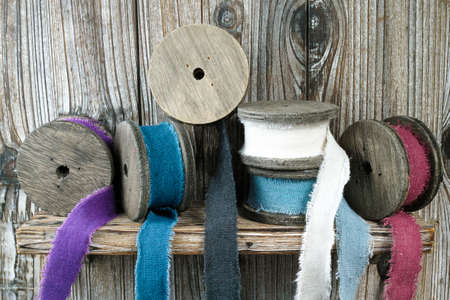 Colorful wooden reels with linen ribbons on wooden background, handmade and hobby conceptの写真素材