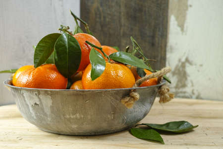 Fresh mandarin oranges fruit with green leaves on wooden backgroundの写真素材