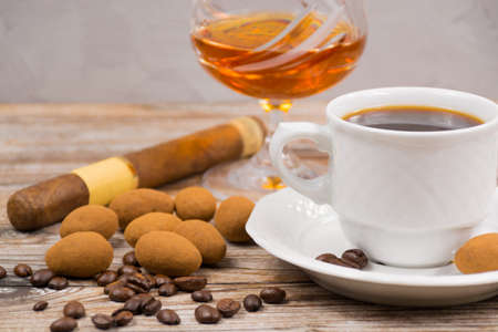 Cigar and  amber color brandy with cup espresso,  coffee beans  and chocolate eggs on wooden backdroundの写真素材