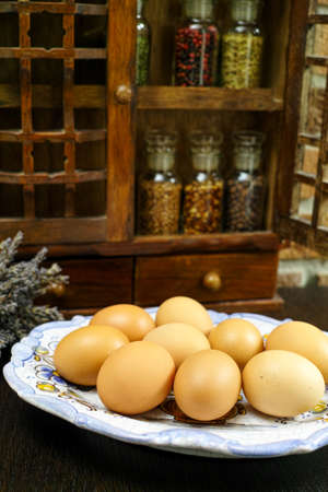 Farms vintage Spice Rack or Storage Cabinet: Wall Mount - Display Shelf, Two Drawers, Six Glass Bottles on rural background with fresh organic eggs, village lifeの写真素材