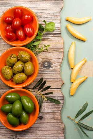 Tapas orange bowls  with giant  green olives and cherry tomatoes on wooden background, copy spaceの写真素材