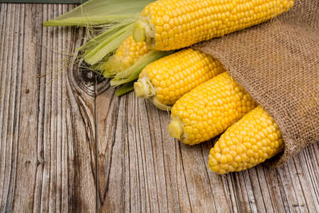 Fresh corn with leaves on wooden backgroundの写真素材
