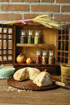 Round Loaf of Home made Bread with onion, whole wheat, in rural style on brick wall background