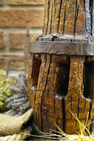 Antique wooden wheel hub on burlap sack against rural brick wall with lavender, oregano, whole wheatの写真素材