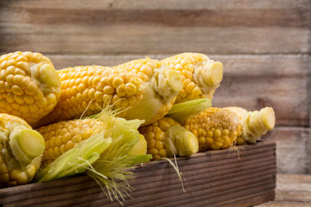 Fresh corn with leaves on wooden backgroundの写真素材