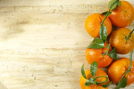 Fresh mandarin oranges fruit with green leaves on wooden backgroundの写真素材