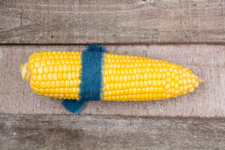 Fresh corn with leaves on wooden backgroundの写真素材
