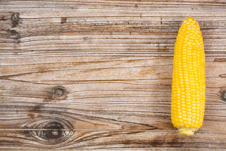 Fresh corn with leaves on wooden backgroundの写真素材