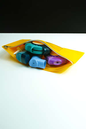 Asthma relief concept, salbutamol inhaler, another medication and yellow medical plastic bag, copy space, isolated on whiteの写真素材
