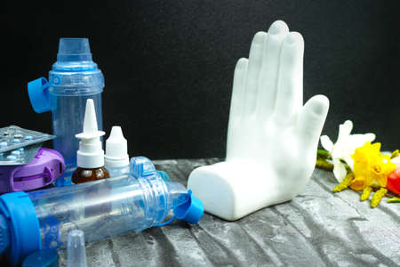 Stop asthma of allergy concept, seasonal pollen and blossom allergy, inhalers and medications with white handの写真素材
