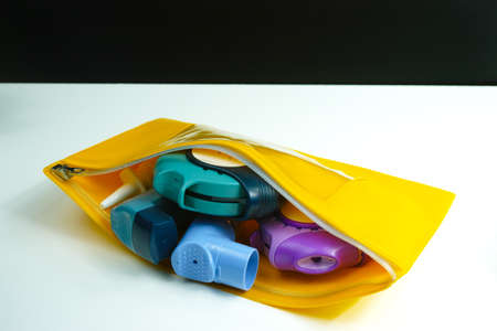 Asthma relief concept, salbutamol inhaler, another medication and yellow medical plastic bag, copy...