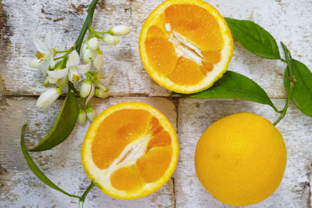 Fresh oranges with leaves and orange tree flowers on rustic wooden backgroundの写真素材