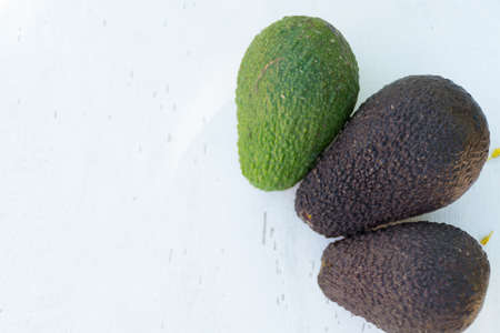 Fresh green ripe avocado on white wooden background copy space