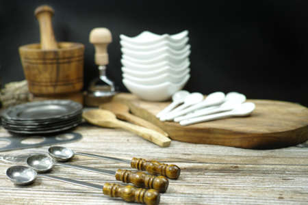 Different kitchen accessories from tin, olive wood and ceramic on black and wooden backgroundの写真素材
