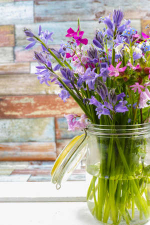 Jar with fresh colorful bouquet spring forest flowers and hyacinths, mothers day conceptの写真素材