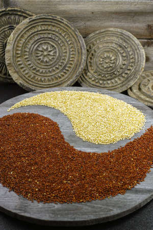 White and black quinoa yin yang on black background with old ornamental stonesの写真素材